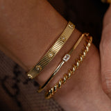 Gold bracelets on a wrist with a blurred background