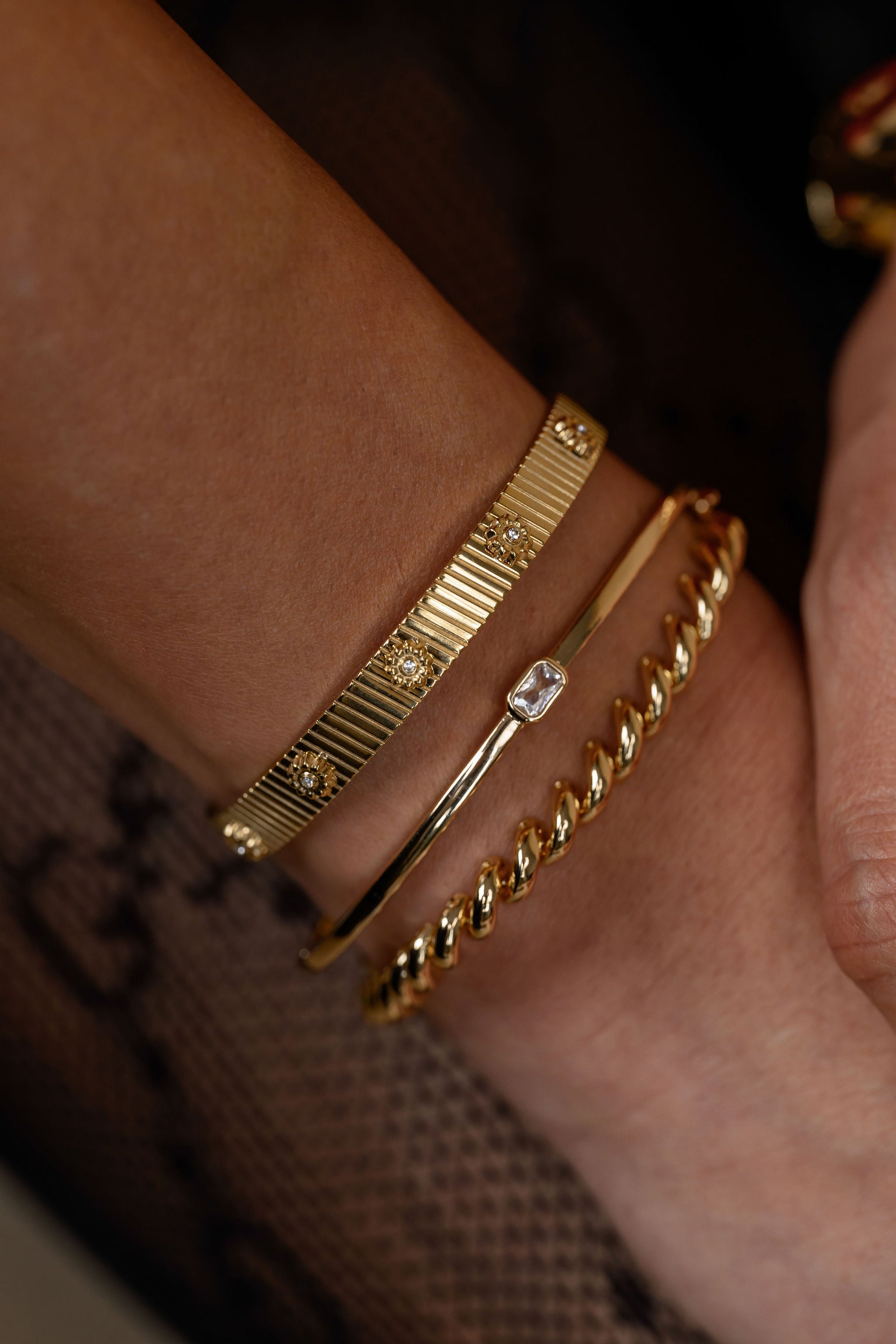 Gold bracelets on a wrist with a blurred background
