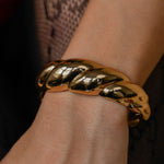 Gold bracelet on a wrist with a dark background
