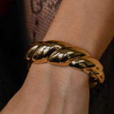 Gold bracelet on a wrist with a dark background