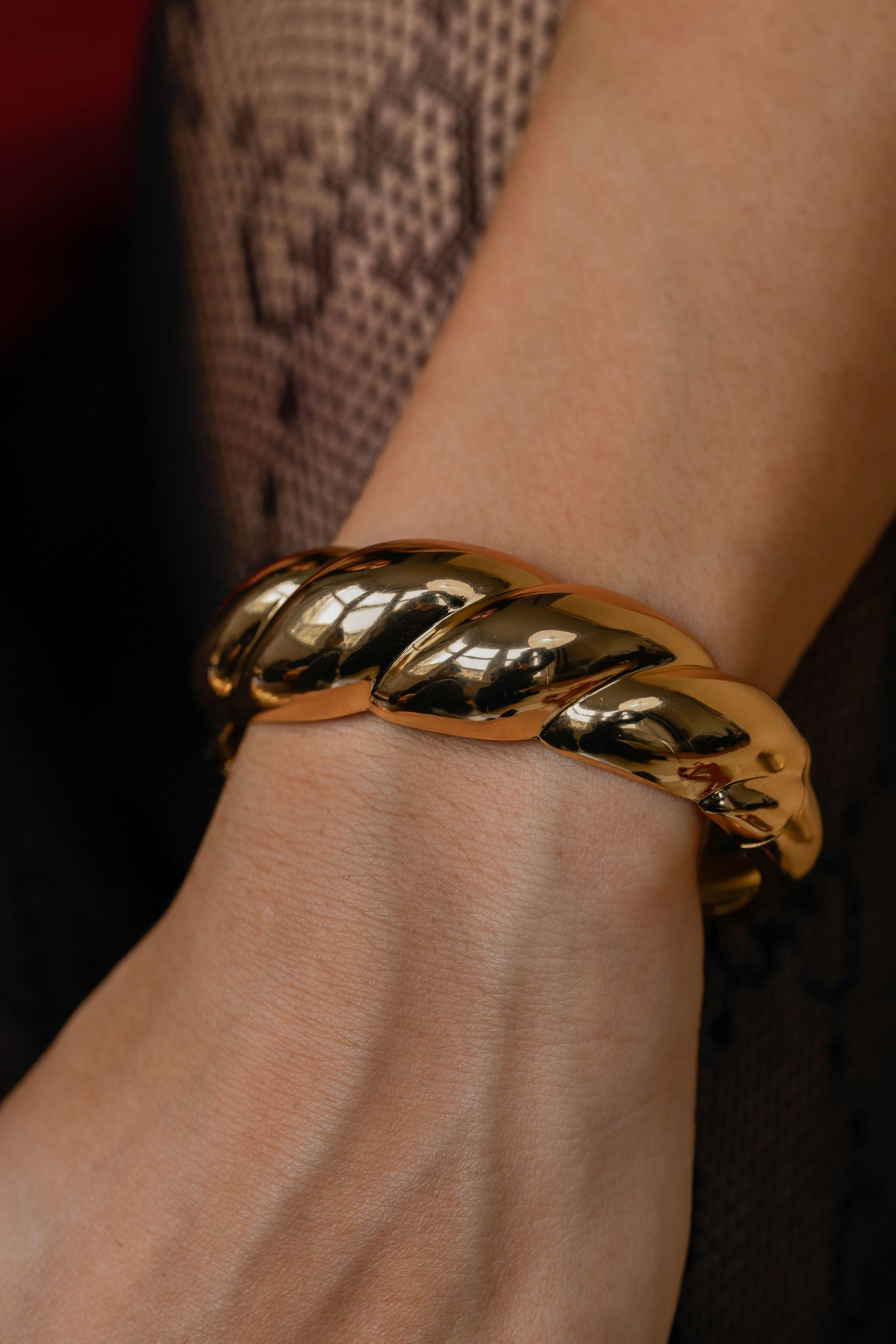 Gold bracelet on a wrist with a dark background