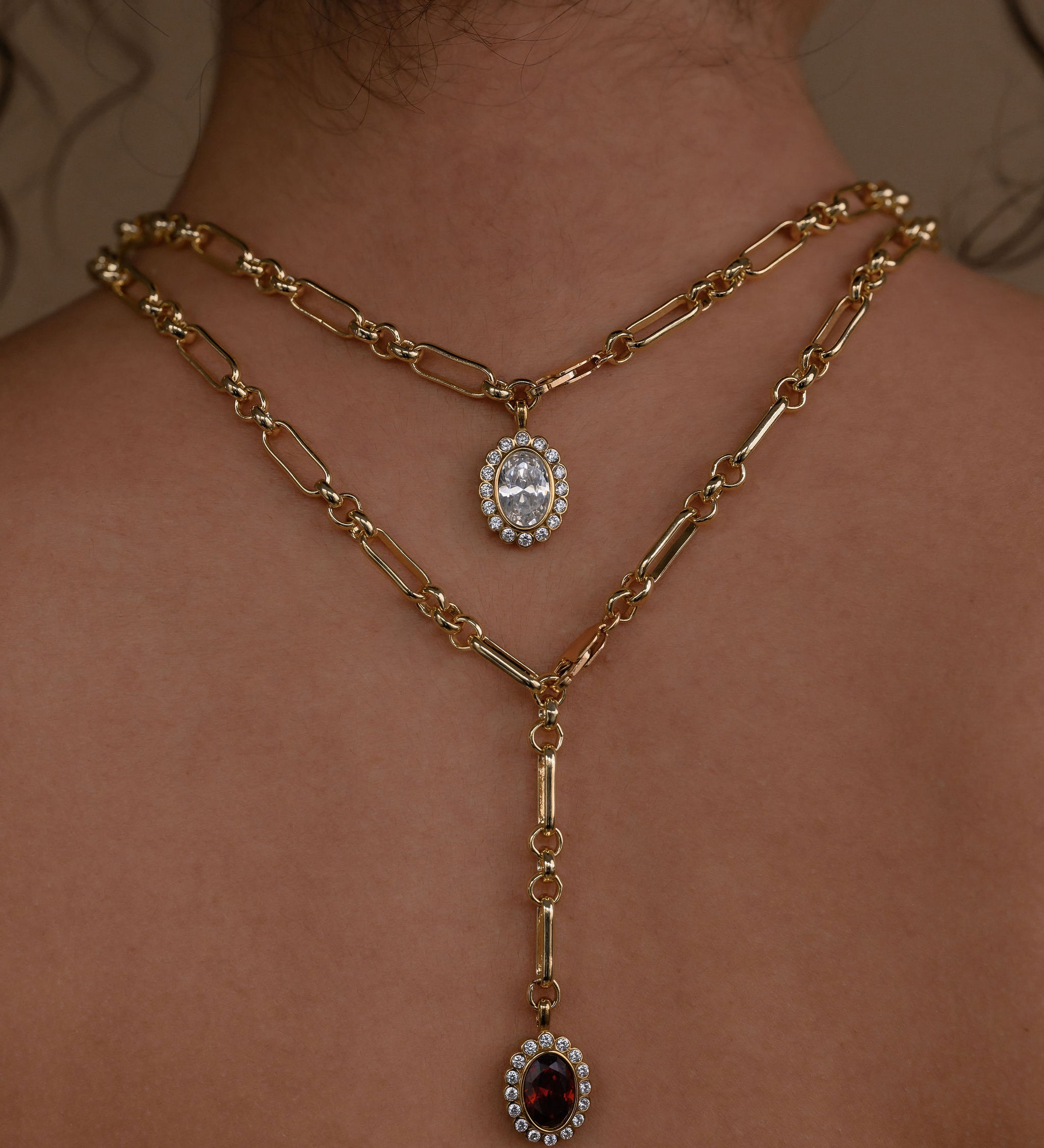 Gold chain necklaces with pendant drops on a person's neck