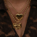 Gold necklace with heart and bow pendants on a lace garment.