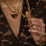 Close-up of a person wearing gold chain necklaces and rings on a dark background