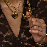 Close-up of a person wearing gold chain necklaces and rings on a dark background