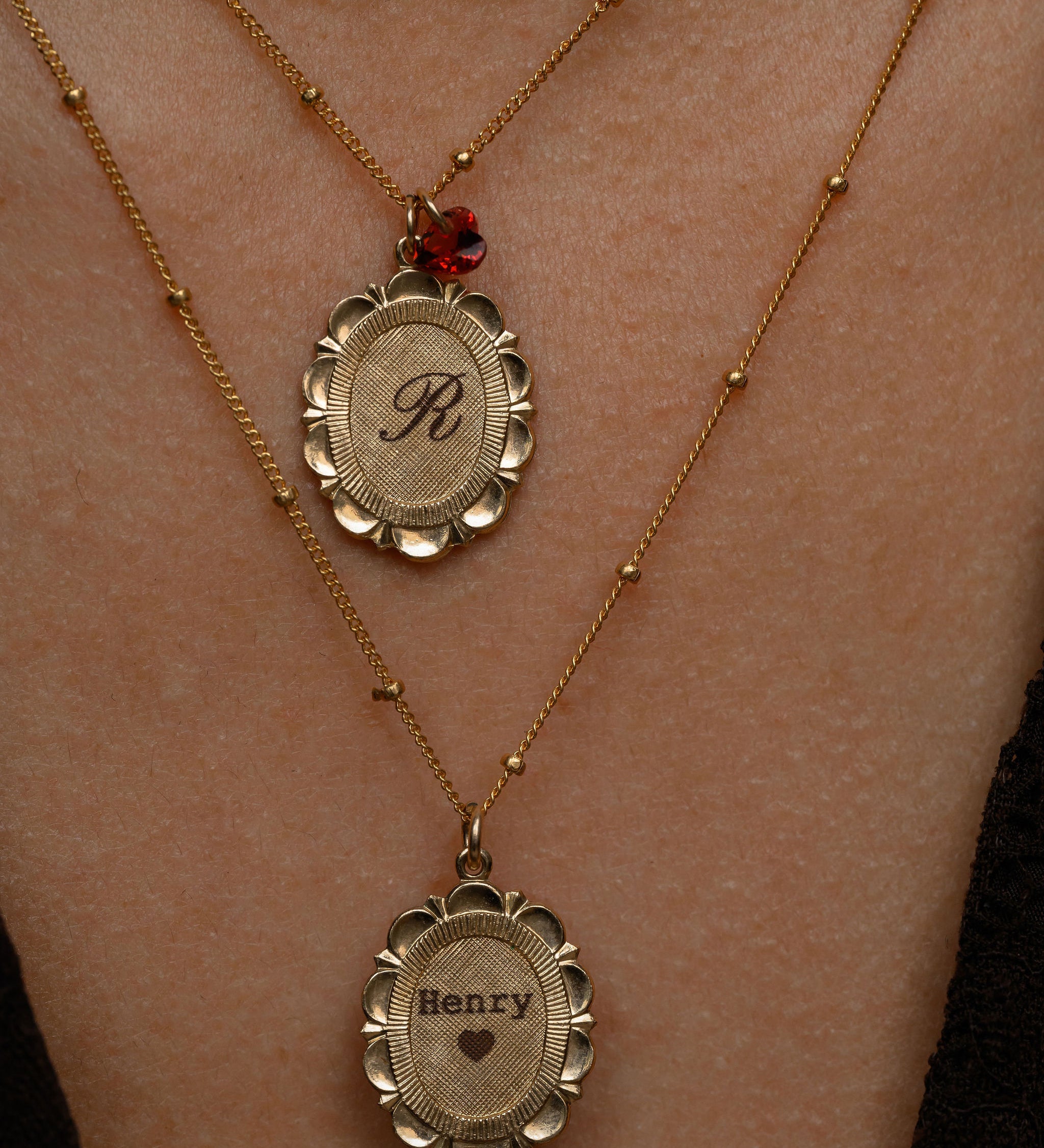 Two gold necklaces with engraved names on a person's neck.