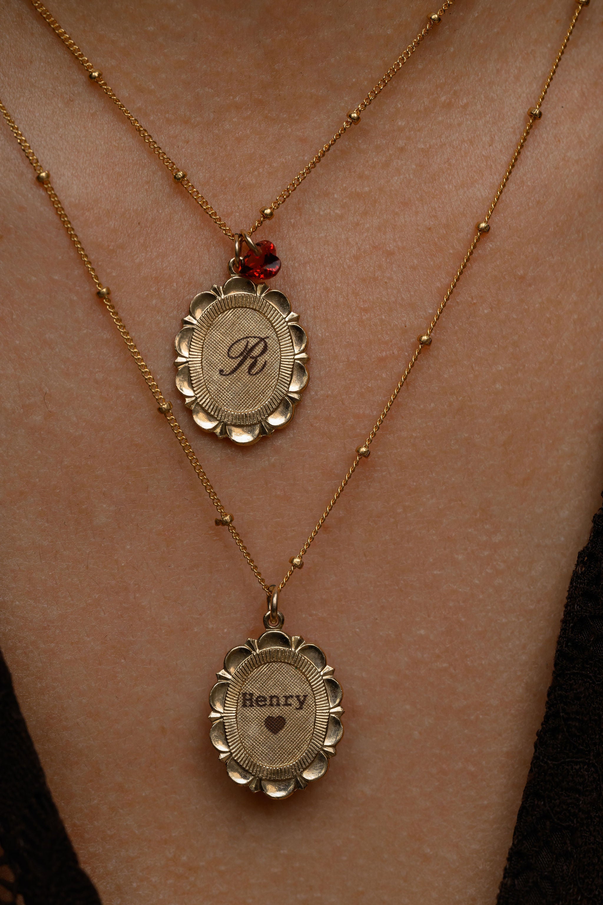 Two gold necklaces with engraved names on a person's neck.