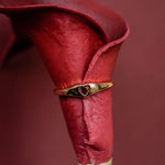 Gold ring with a heart design on a red flower against a red background