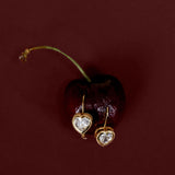 Heart-shaped earrings on a dark red background