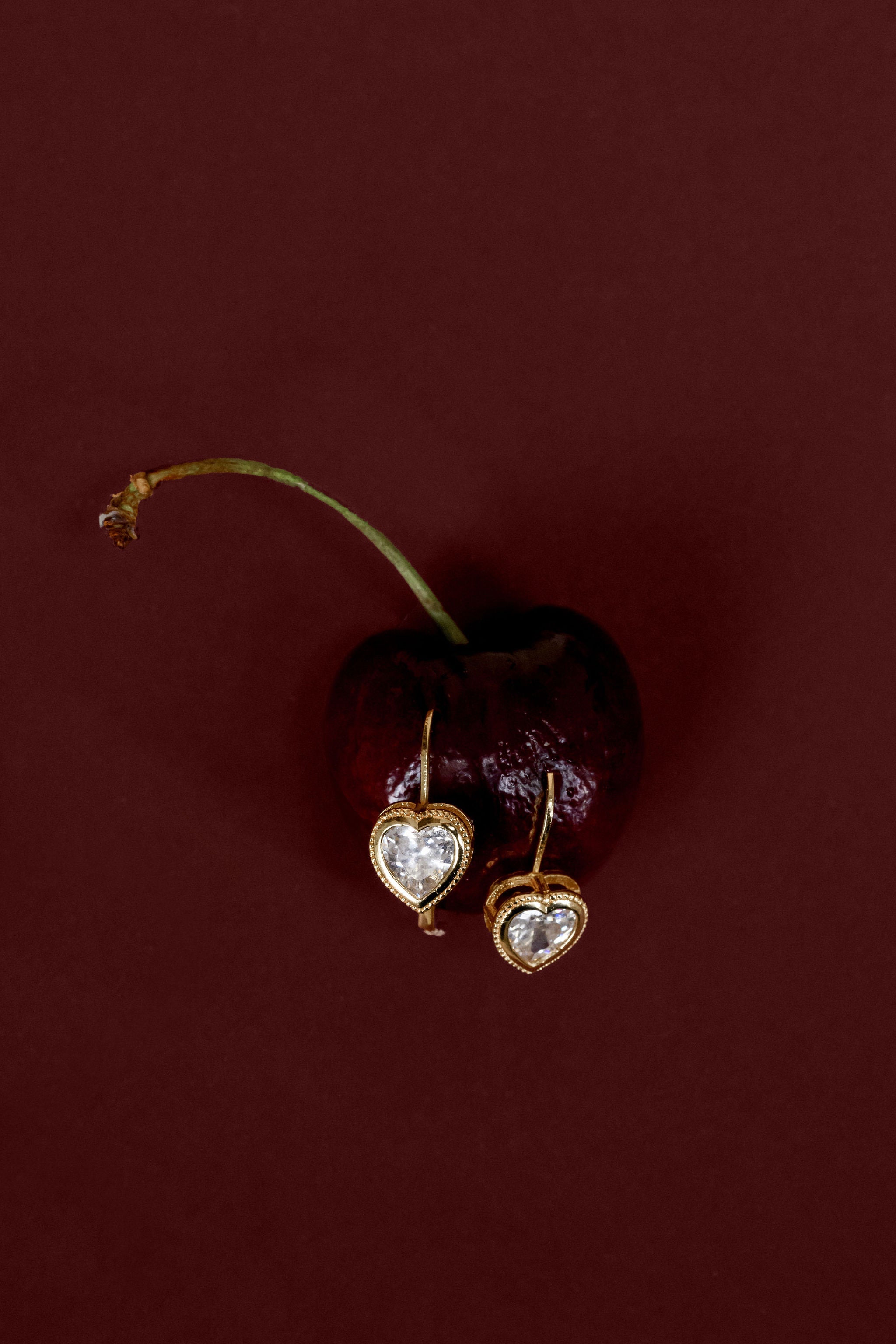 Heart-shaped earrings on a dark red background