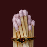 Matchstick with a gold ring featuring a red gemstone on a dark background