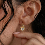 Close-up of a woman wearing a gold earring with a heart design.