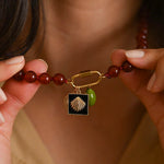 Close-up of a person holding a beaded bracelet with a shell charm.