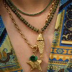 Model wearing the Pez necklace in evergreen gemstones layered with beaded strands