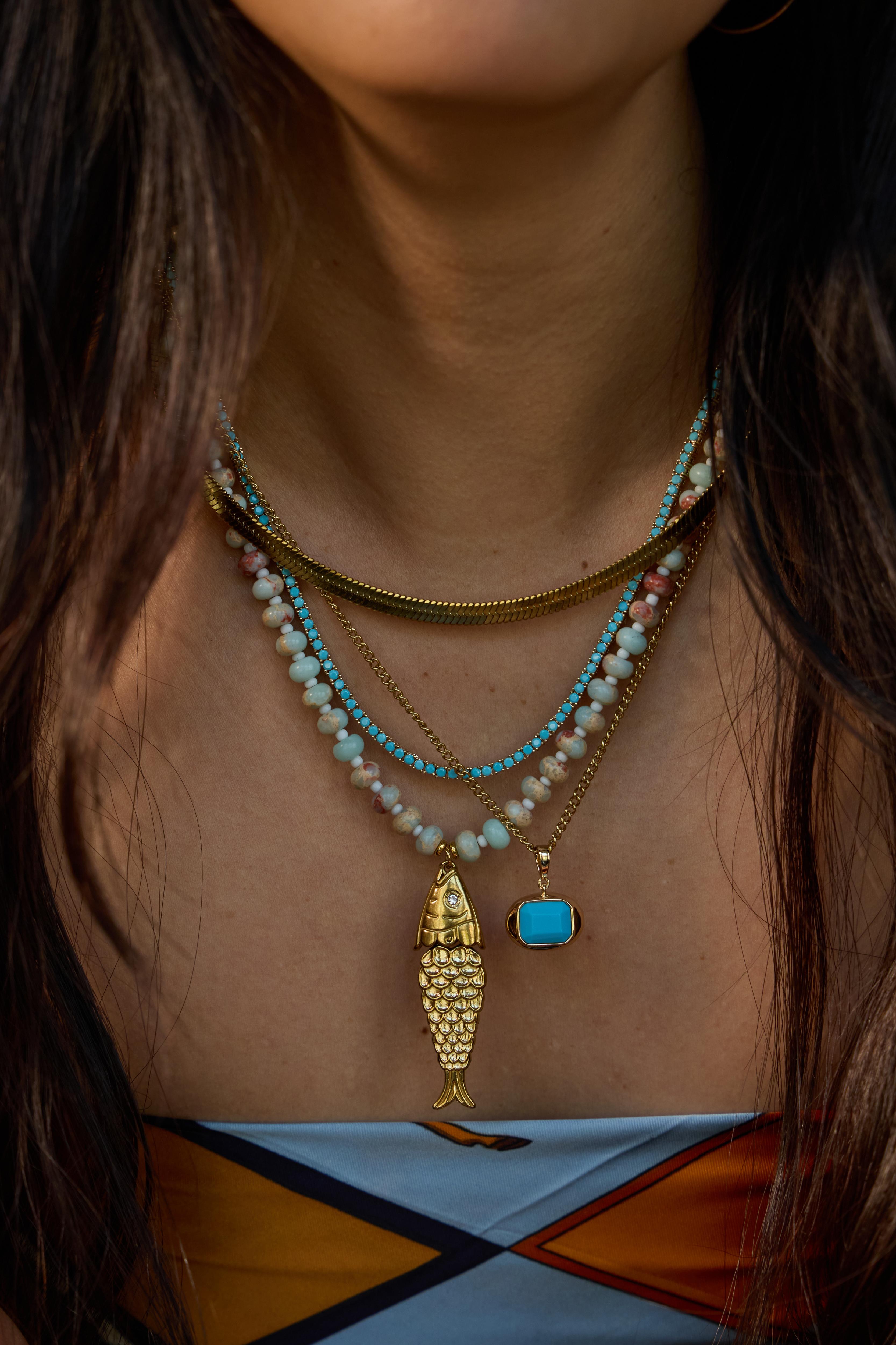 Model wearing the turquoise Pez necklace with its articulated fish charm