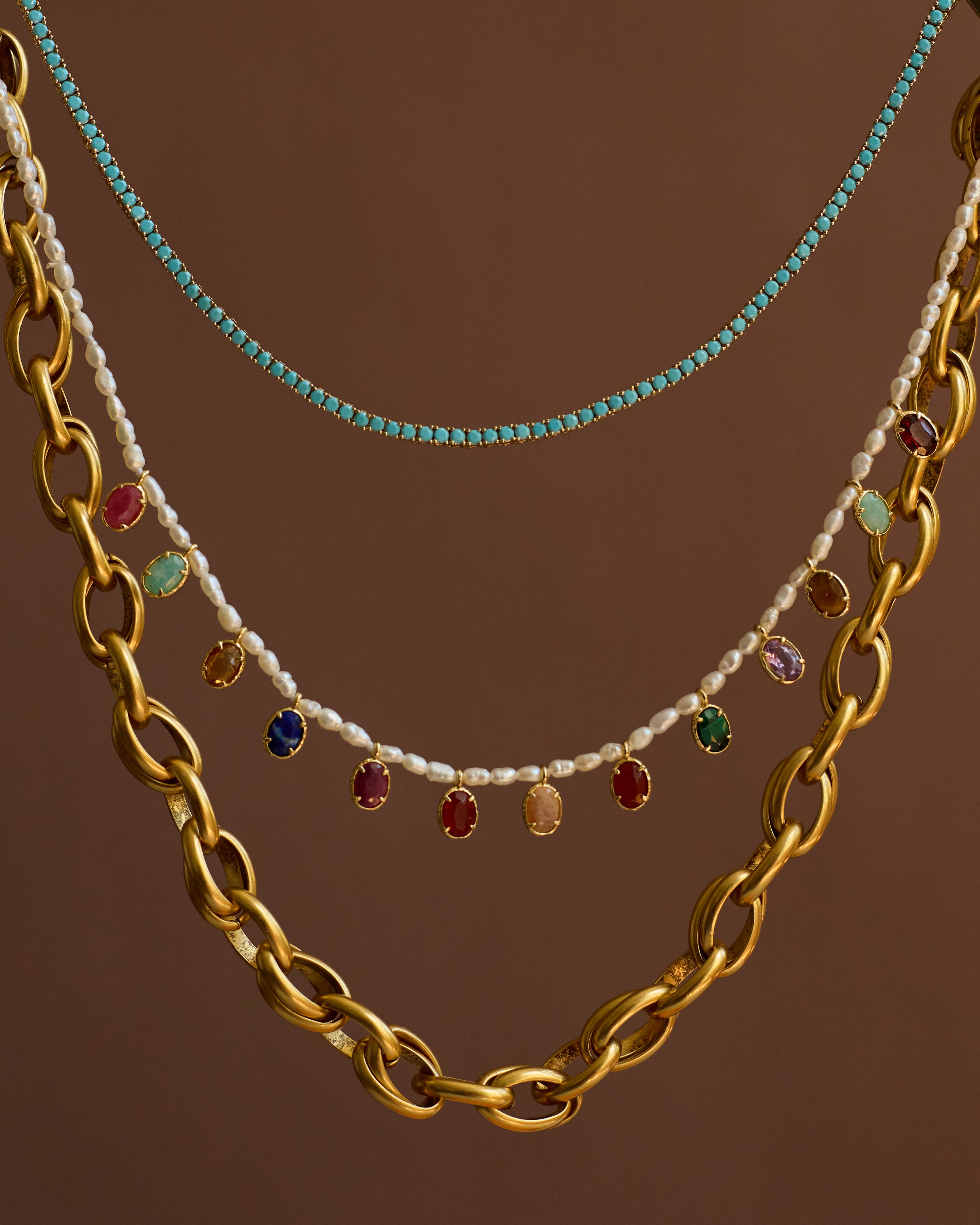 Three necklaces with different designs on a brown background