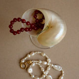 Red beaded necklace and white pearl necklace on a beige surface