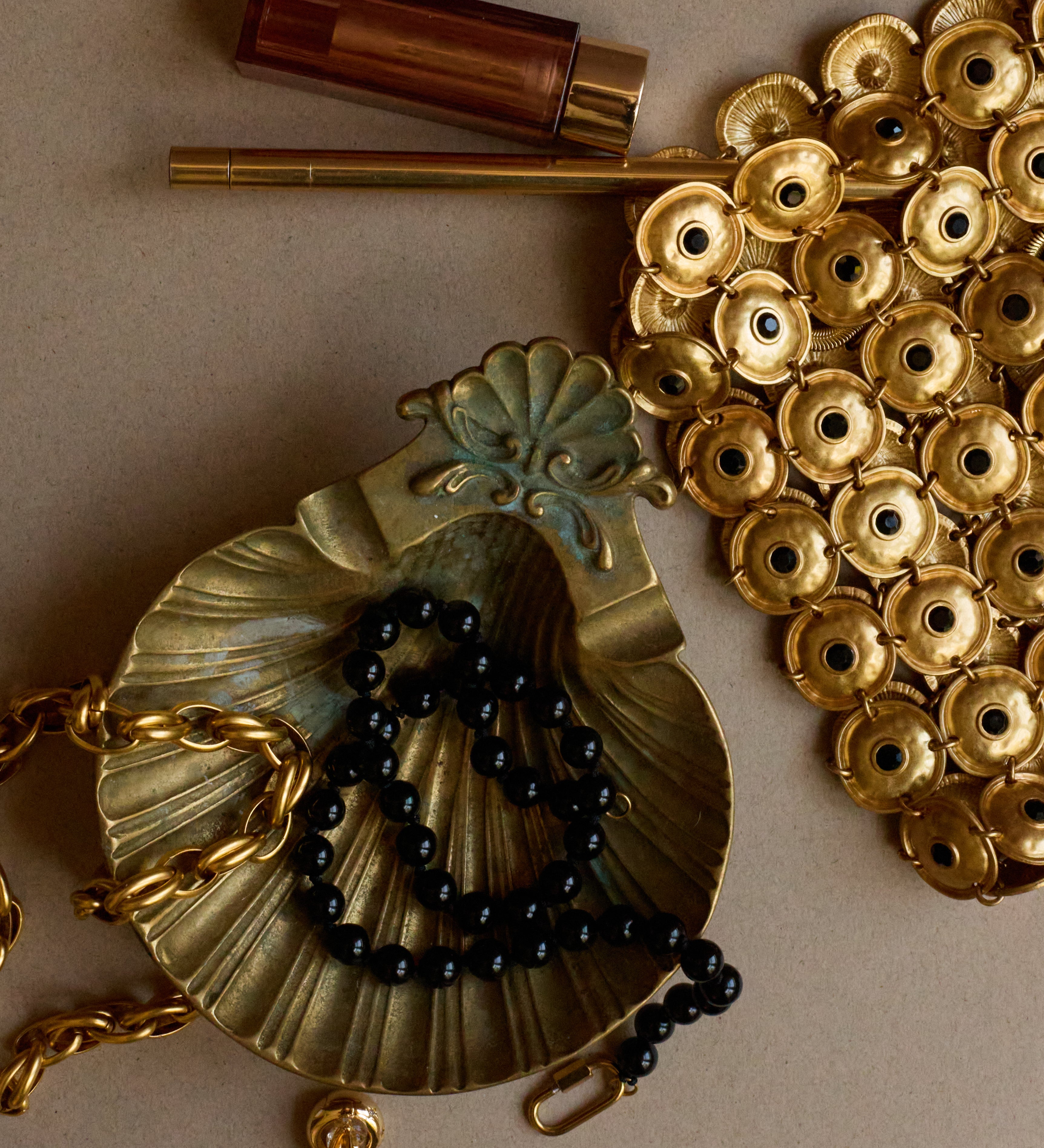Gold necklace with black beads and decorative elements on a beige background