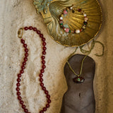Jewelry display with a gold shell, beads, and a mannequin torso on a textured surface.