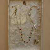 Jewelry set with pearls and gemstones on a textured surface