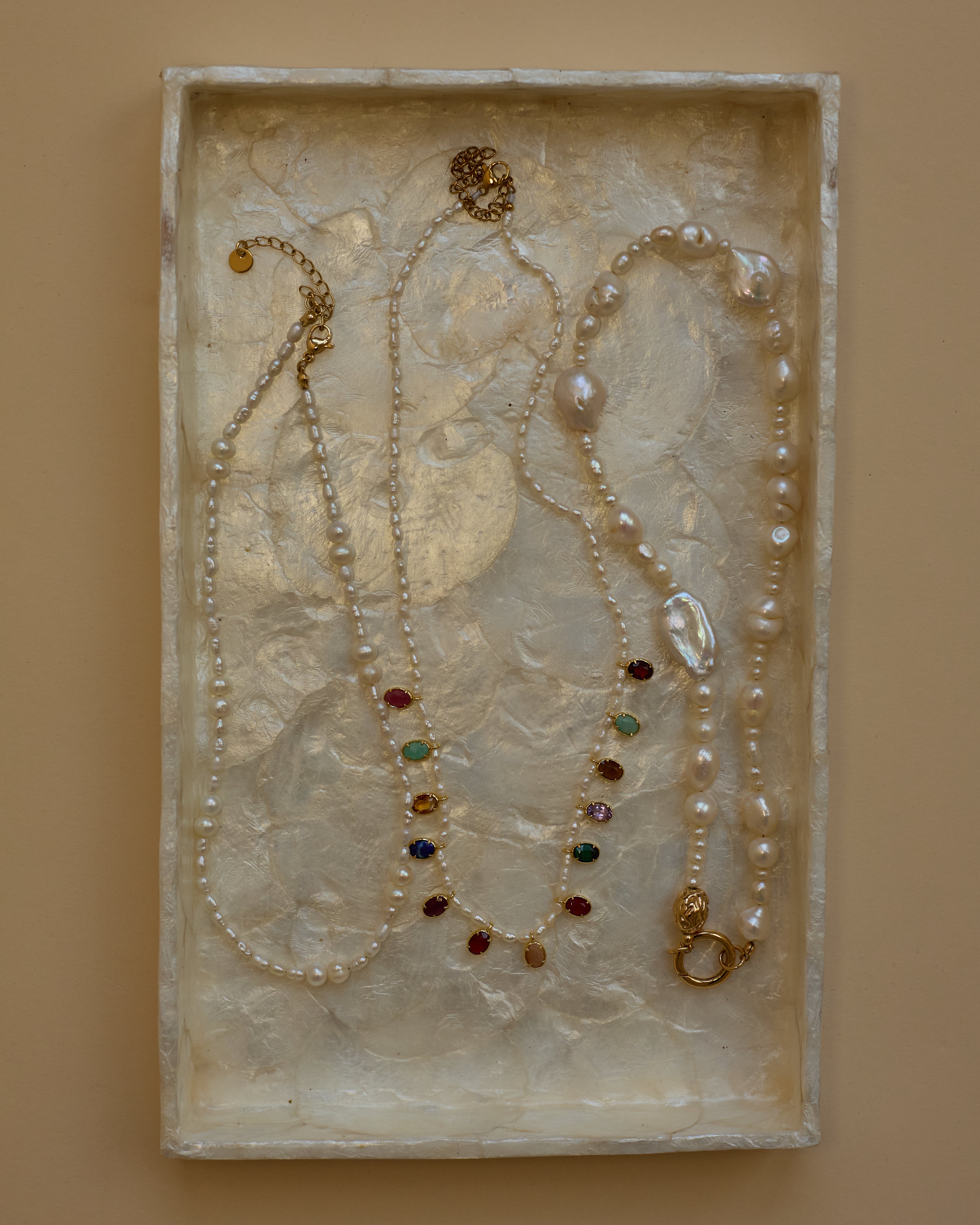 Jewelry set with pearls and gemstones on a textured surface