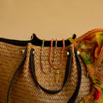 Woven bag with colorful beads and a multicolored fabric on a beige background