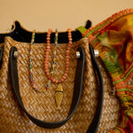 Woven handbag with colorful beads and a fish charm on a beige background