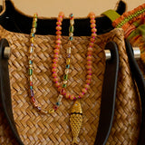 Woven bag with colorful beaded necklace and fish pendant on a beige background