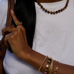 Person wearing multiple bracelets and rings on a white background
