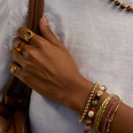 Hand with multiple bracelets and rings on a white background