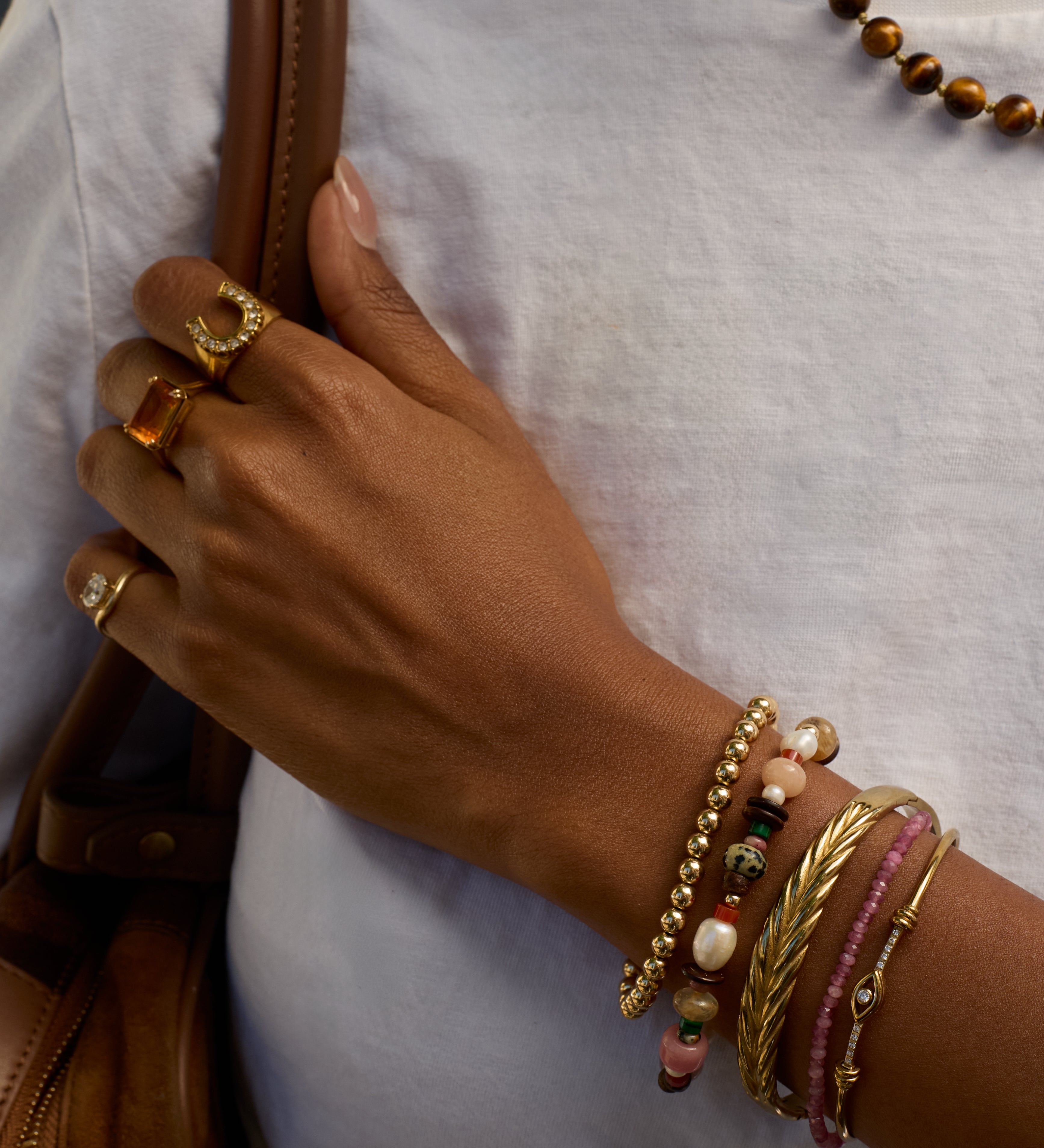 Hand with multiple bracelets and rings on a white background