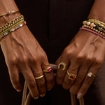 Close-up of hands wearing gold jewelry with a dark background