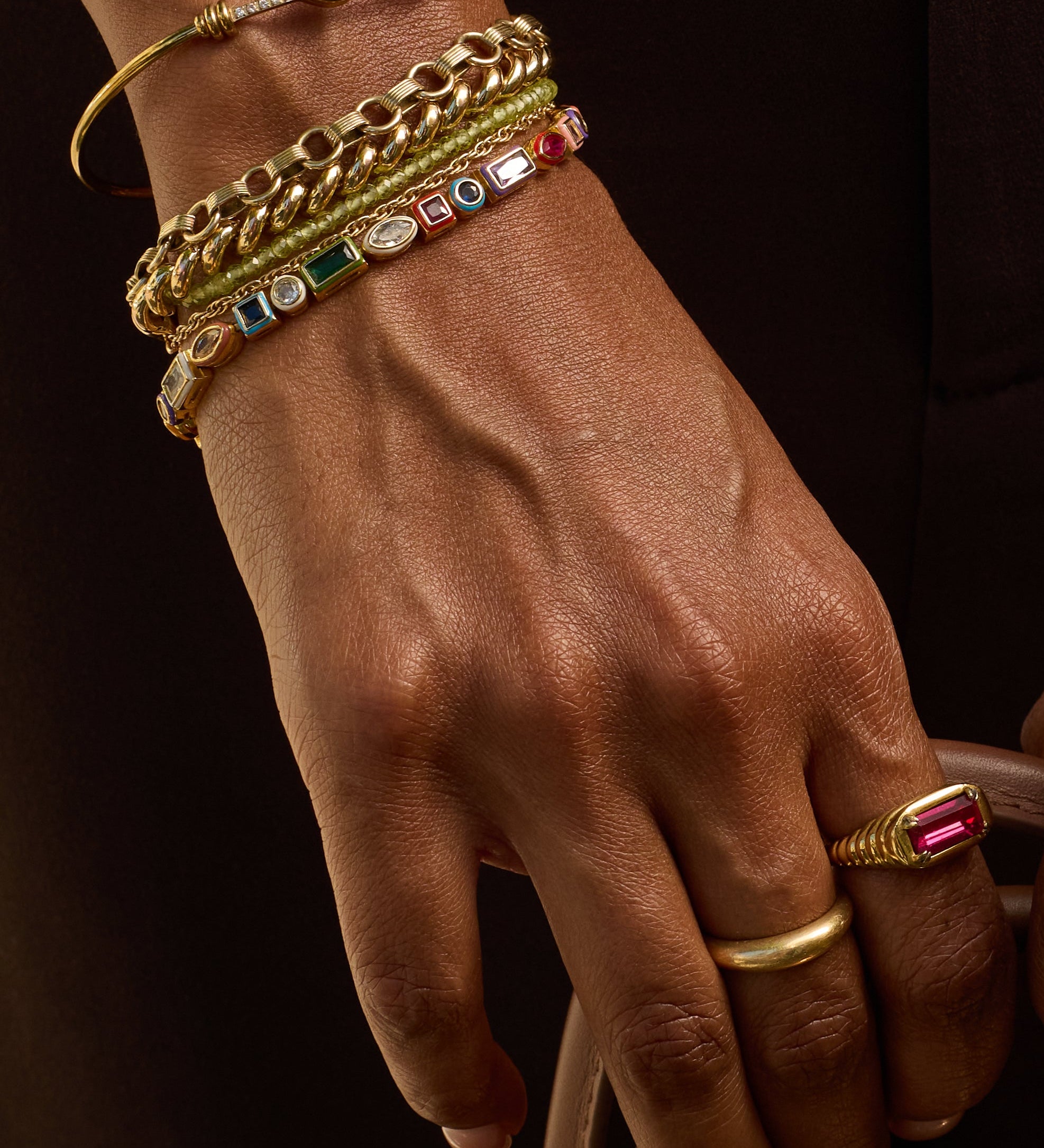 Close-up of hands wearing gold jewelry with a dark background