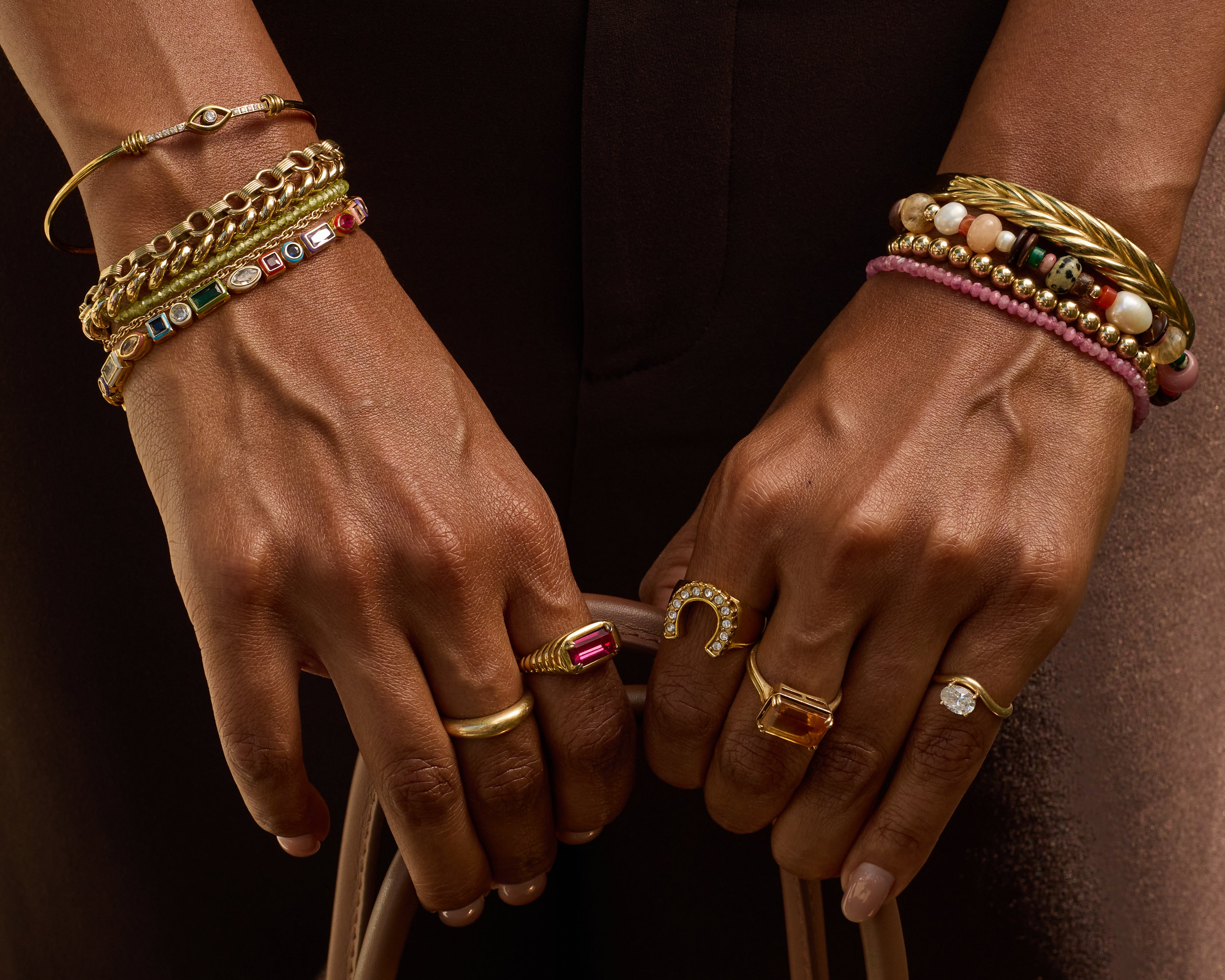 Close-up of hands wearing gold jewelry with a dark background