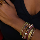 Close-up of a person's arm wearing multiple colorful bracelets on a black background
