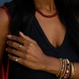 Close-up of a person wearing multiple rings and bracelets with a dark background