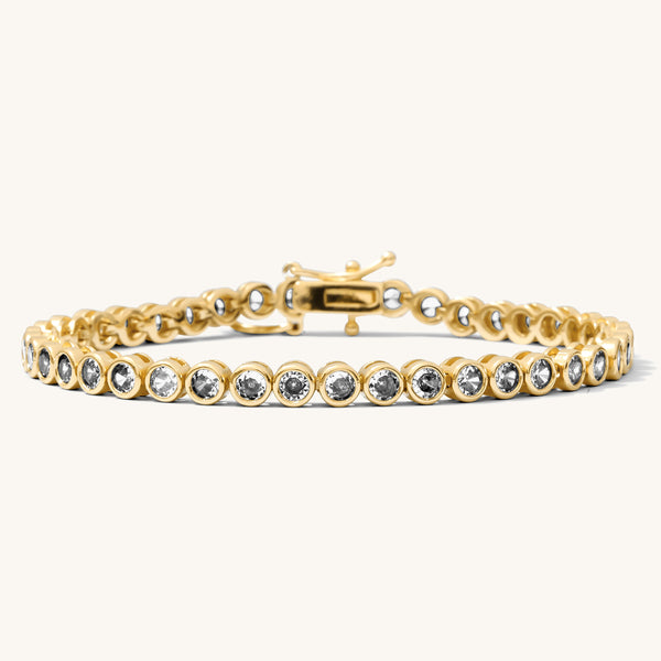 Close up of a gold bracelet with stones on a white background 