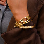 Close up of a person in a brown coat with gold bangles 