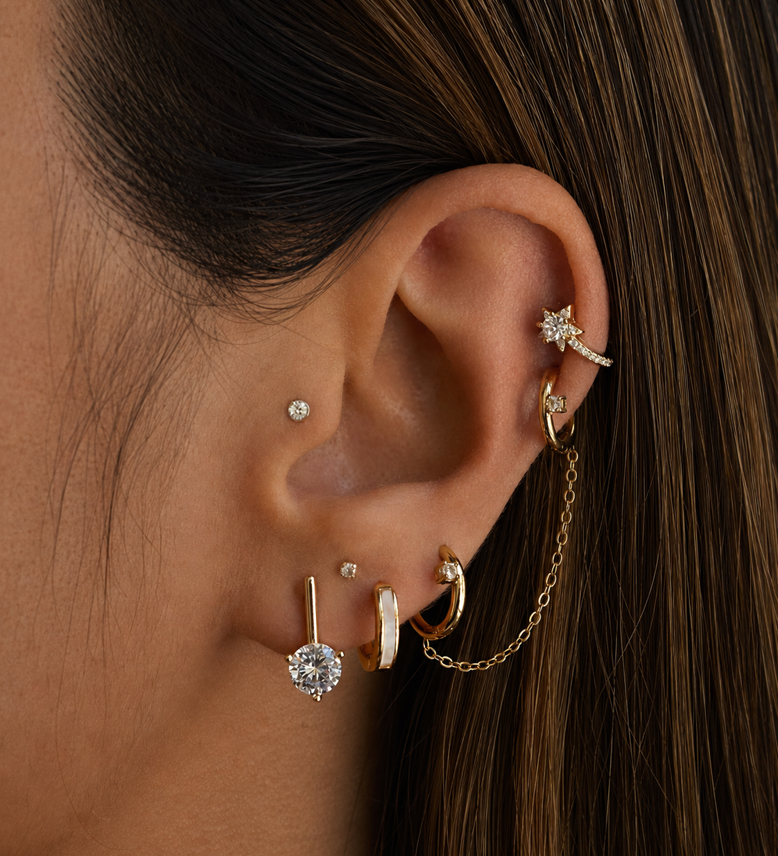 Close-up of an ear with multiple gold and diamond earrings.