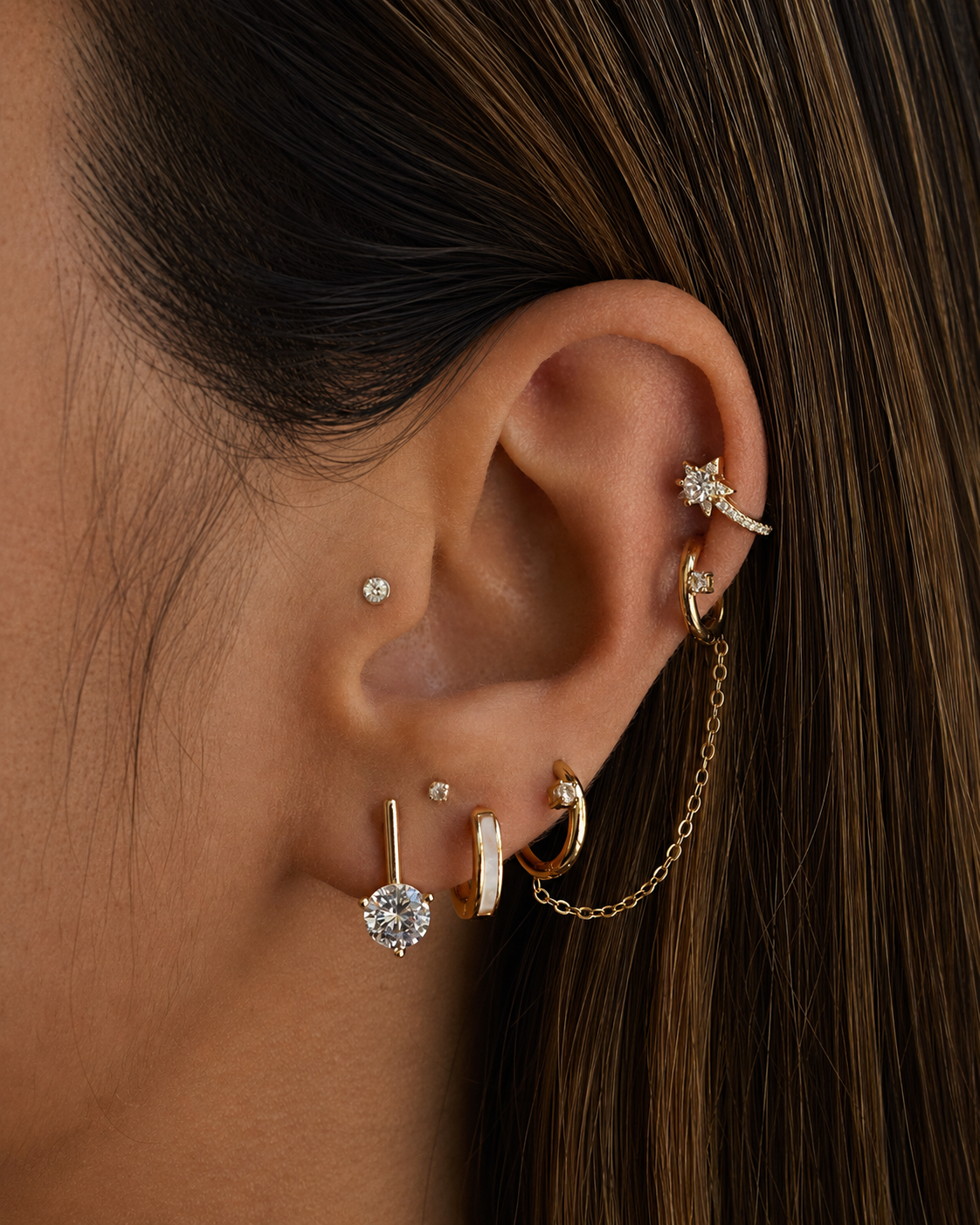 Close-up of an ear with multiple gold and diamond earrings.