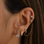 Close-up of an ear with multiple gold and diamond earrings.