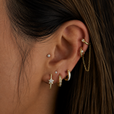 Close-up of an ear with multiple gold and diamond earrings against a dark background