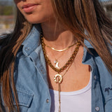 Woman wearing a denim jacket and multiple necklaces outdoors