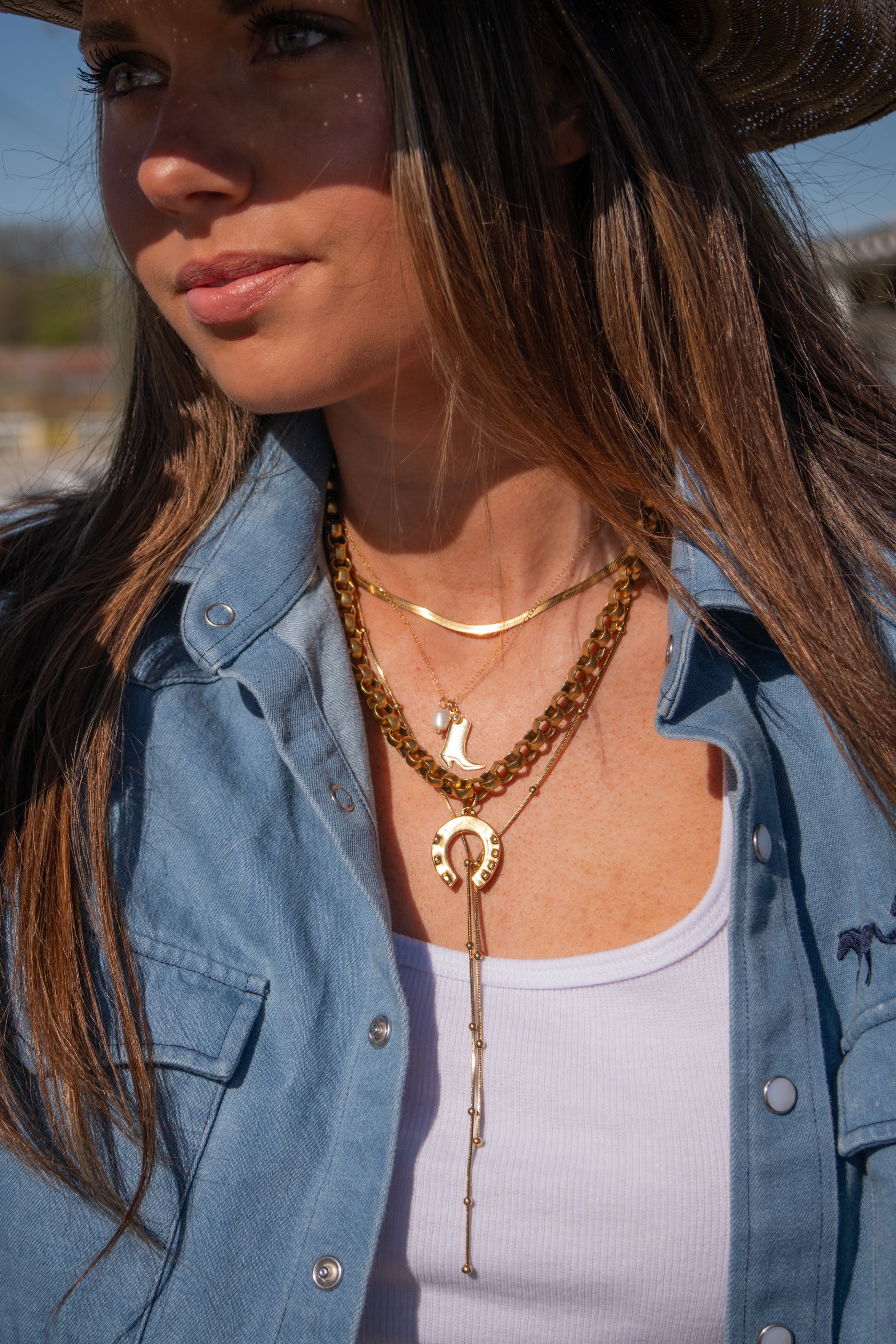 Woman wearing a denim jacket and multiple necklaces outdoors