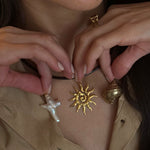 Close-up of a person wearing gold and silver necklaces with sun and star designs.