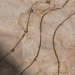 Gold chain necklace on a textured stone surface