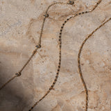 Gold chain necklace on a textured stone surface