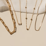 Gold necklaces displayed on a white surface