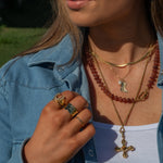 Close-up of a person wearing gold necklaces and rings outdoors
