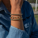 Close-up of a person's wrist wearing multiple bracelets with a blue denim jacket in the background.